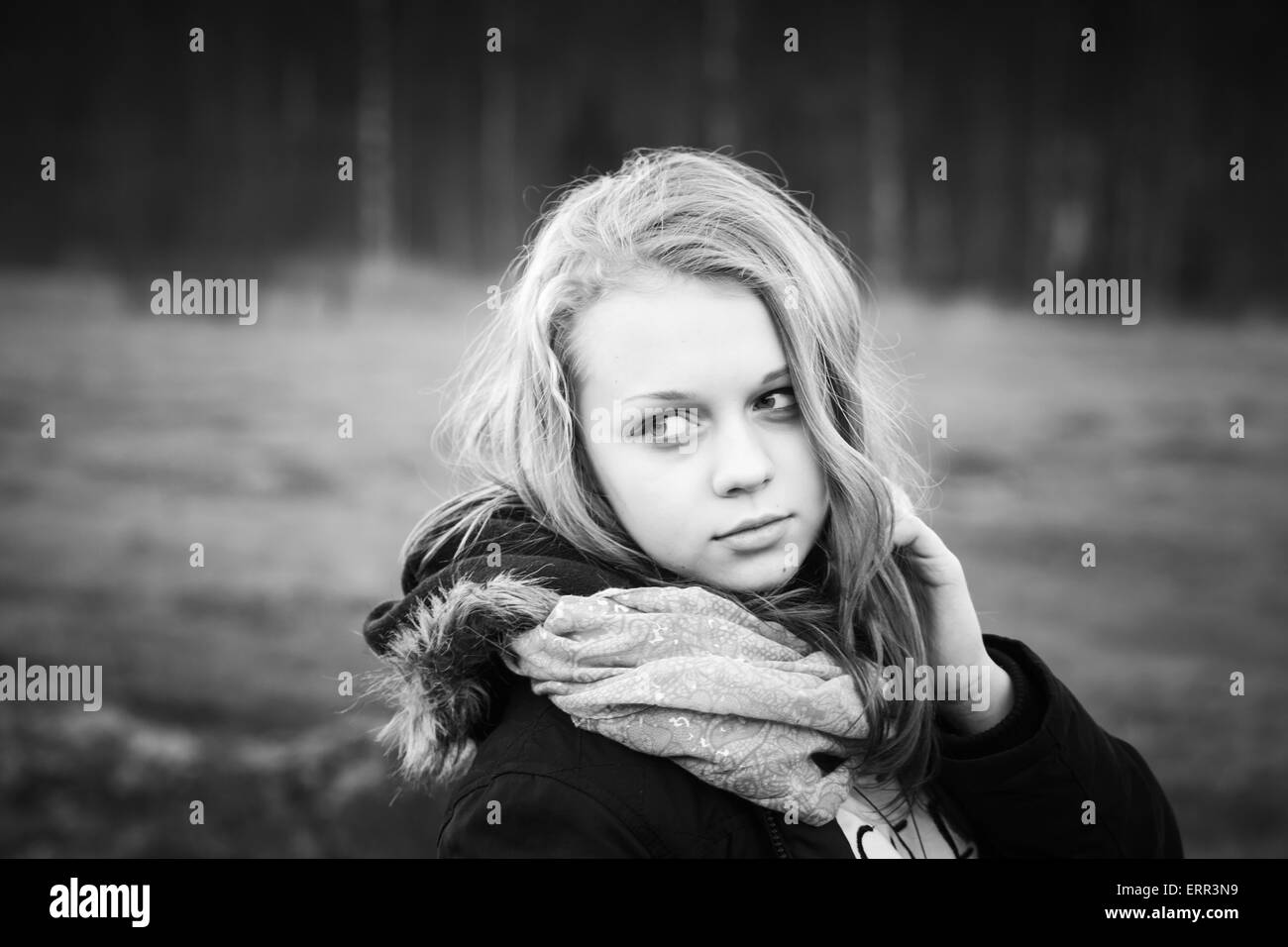 Portrait en extérieur gros plan de beau blond Caucasian teenage girl dans une forêt au printemps, noir et blanc photo stylisée Banque D'Images