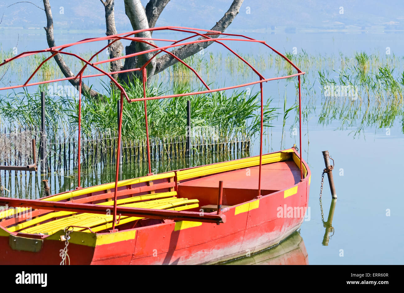 Bateau de pêche rouge sur la rive d'un petit lac Banque D'Images
