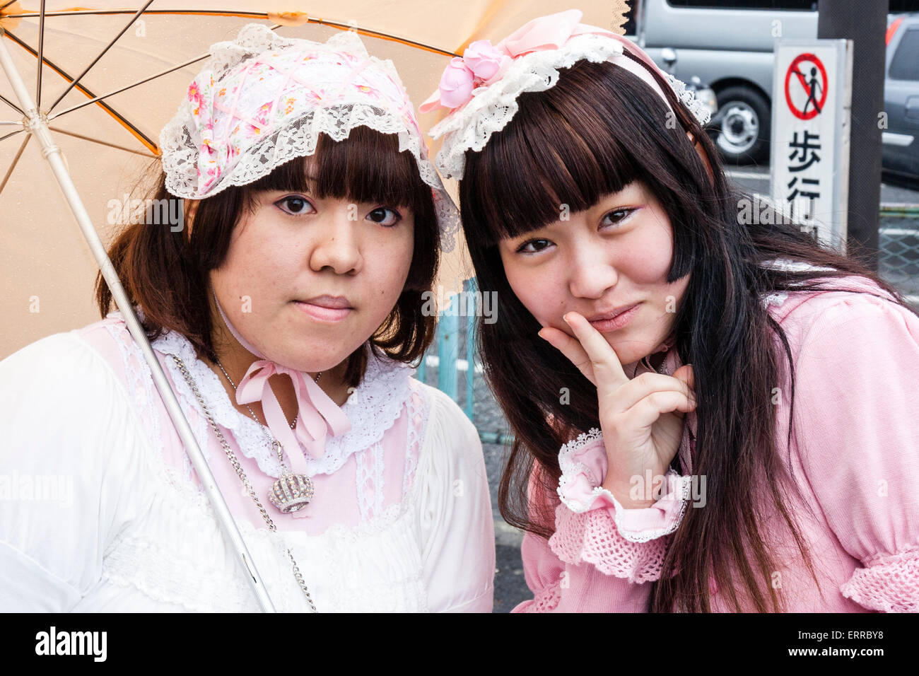 Tokyo, Harajuku. Cosplay. Coup de tête et d'épaule, deux femmes japonaises en vêtements gothiques 'Sweet Lolita', portant un parapluie, on donne le geste de paix. Banque D'Images