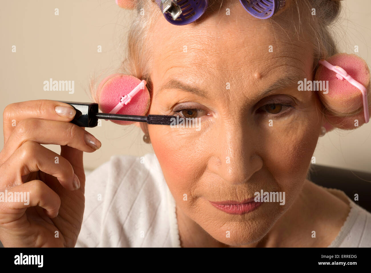 Femme dans les bigoudis mascara Banque D'Images