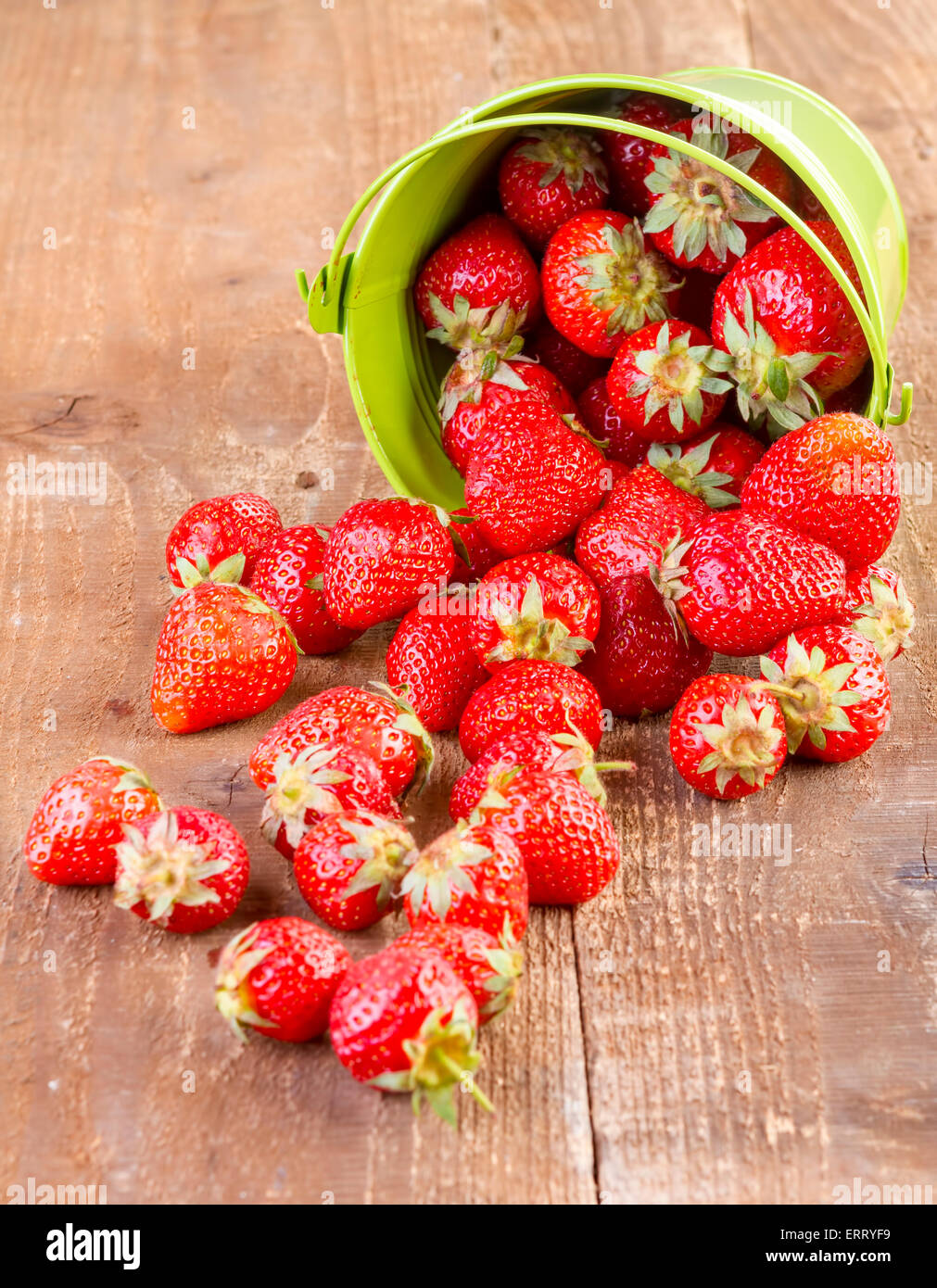 Fraise dans un seau en métal vert sur fond de bois Banque D'Images