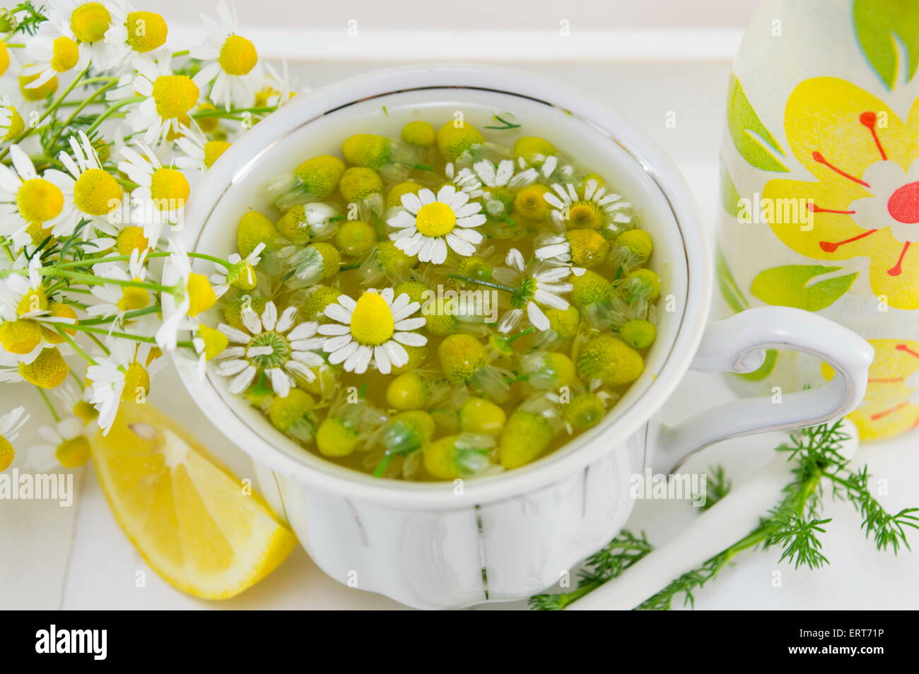 Porcelaine blanche tasse remplie de fleurs de camomille avec citron sur une plaque Banque D'Images