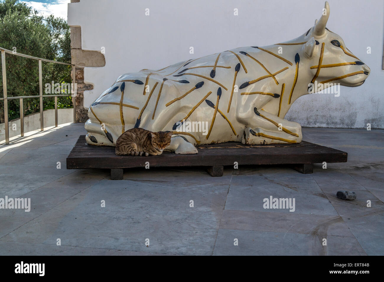 Une statue de moulée en fibre de verre une vache prévue qui est décoré avec des allumettes peintes avec un vrai chat mis à côté de la vache Banque D'Images