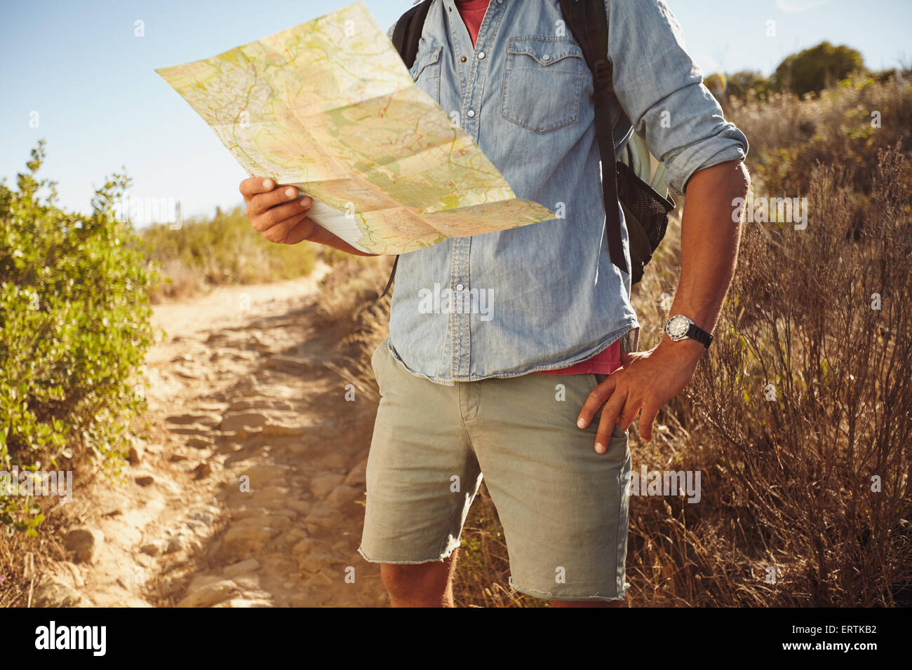 Cropped shot of young man hiking in countryside lire une carte routière pour les directions. Banque D'Images