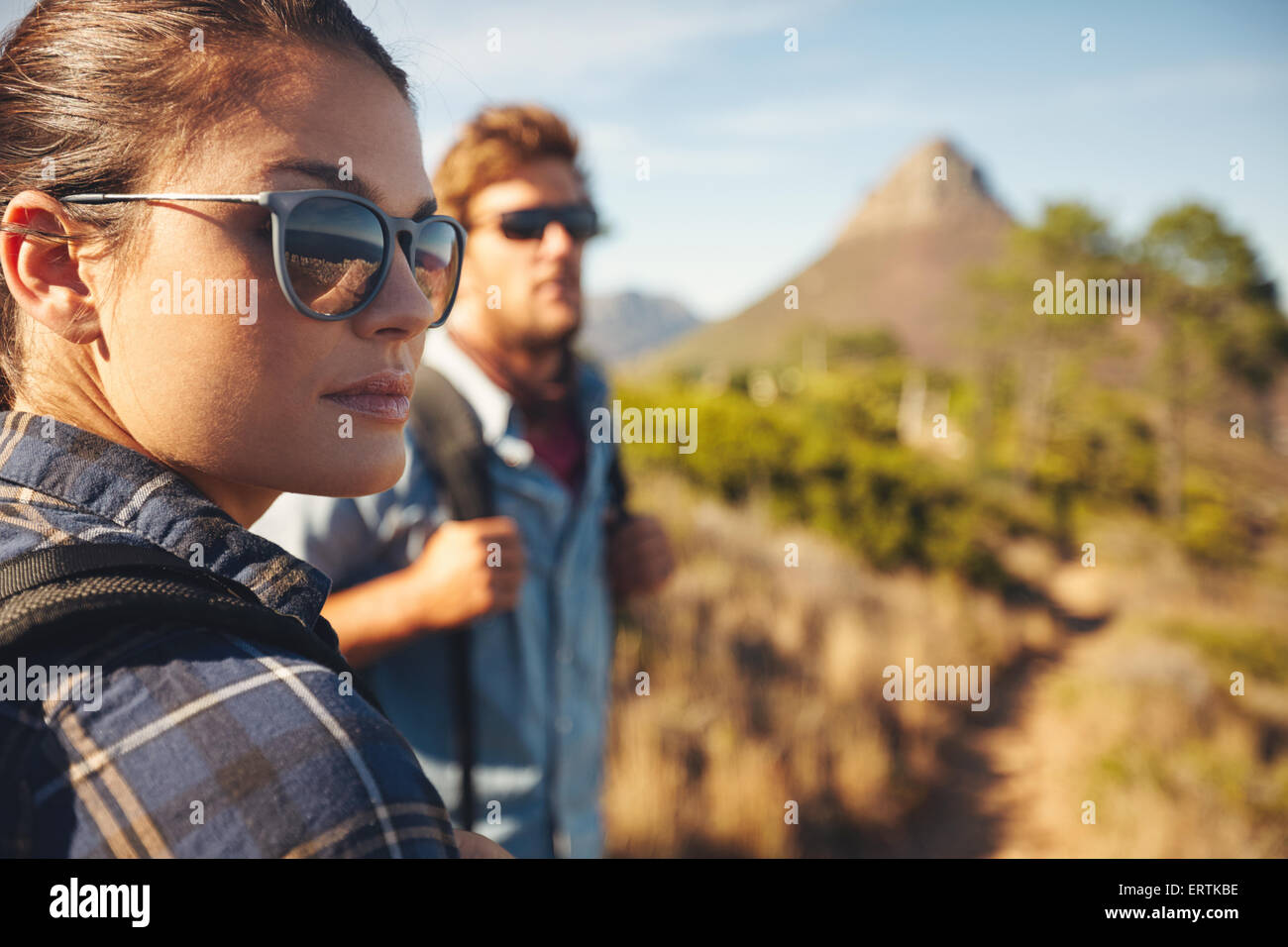 Close up image de jeune femme portant des lunettes de soleil à l'écart avec jeune homme en arrière-plan. Caucasian couple hiking in countrysi Banque D'Images