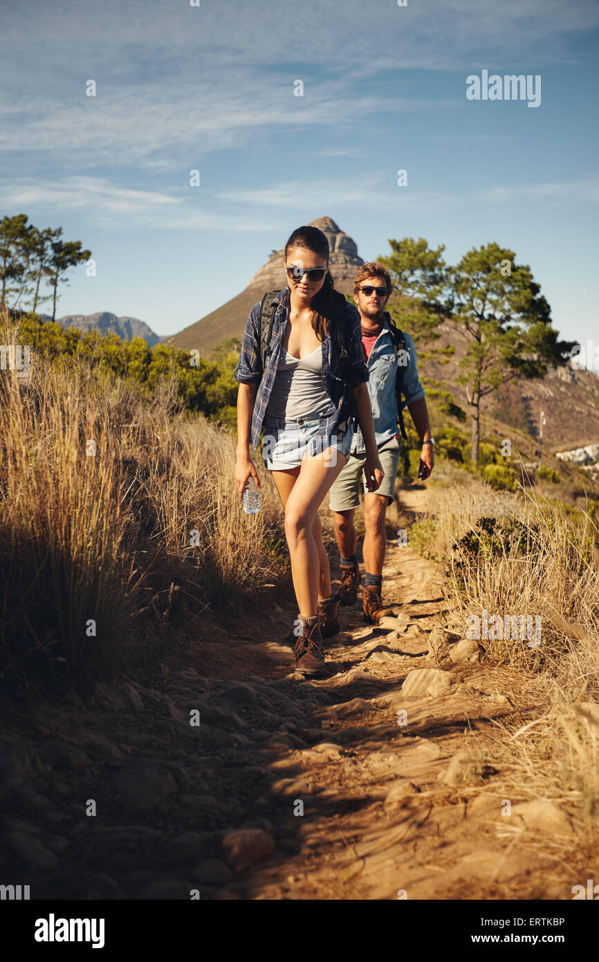 Jeune couple trekking vacances d'été ensemble, dans la campagne au cours d'une journée ensoleillée. Caucasian hiker couple walking par pathwa Banque D'Images
