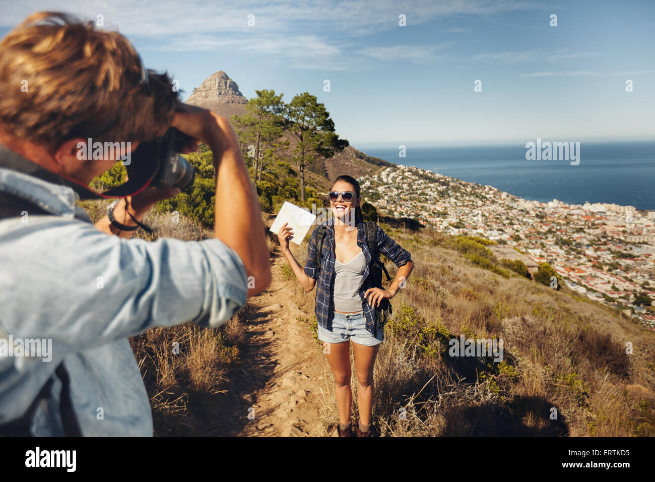 Jeune homme à prendre des photos de la jolie petite amie montrant une carte de campagne tout en randonnée pendant les vacances d'été. Jeune couple bonjour Banque D'Images