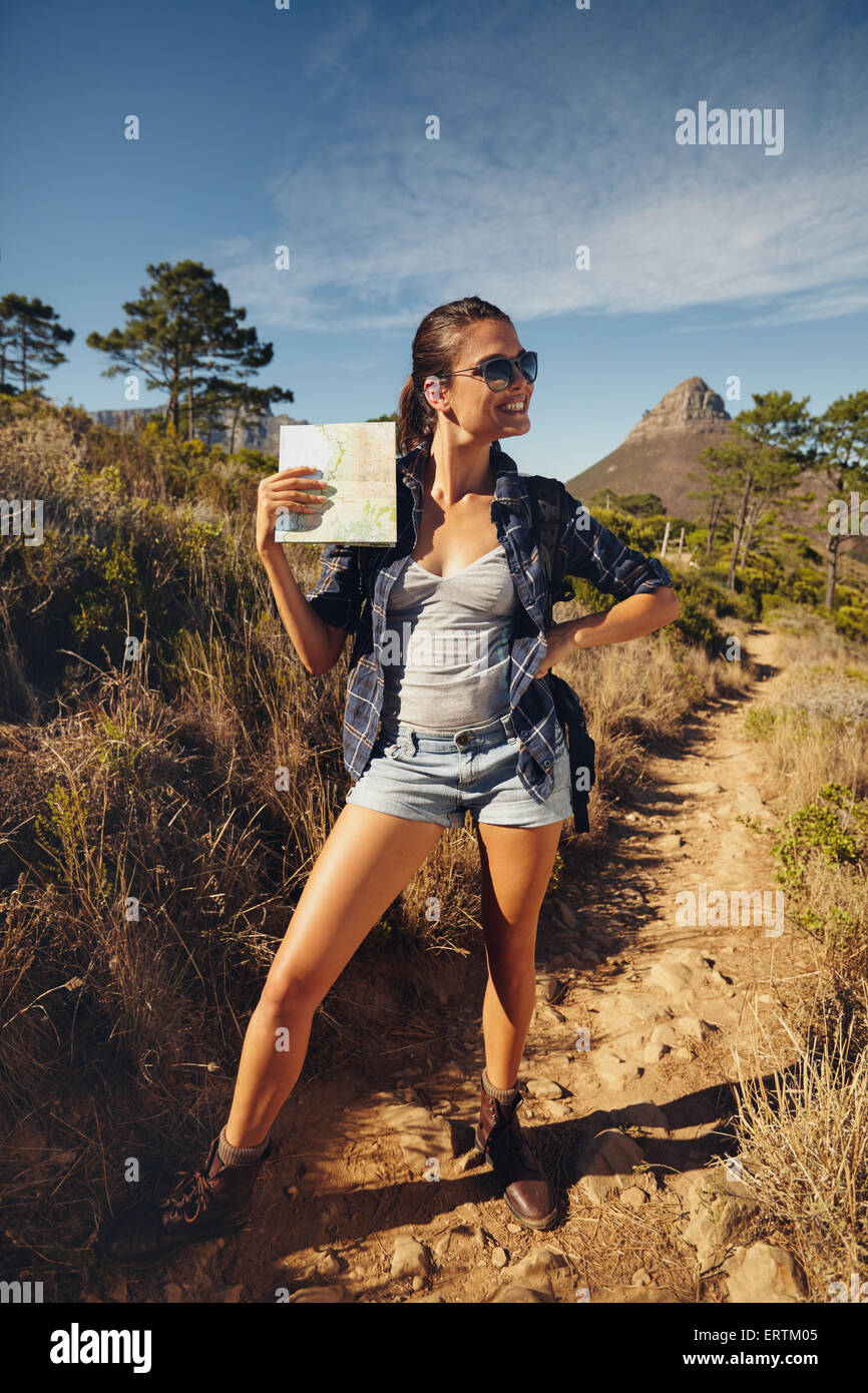 Portrait de belle jeune femme posant avec une carte à l'extérieur. Caucasian woman hiking dans une journée d'été, à la voiture en souriant. Banque D'Images