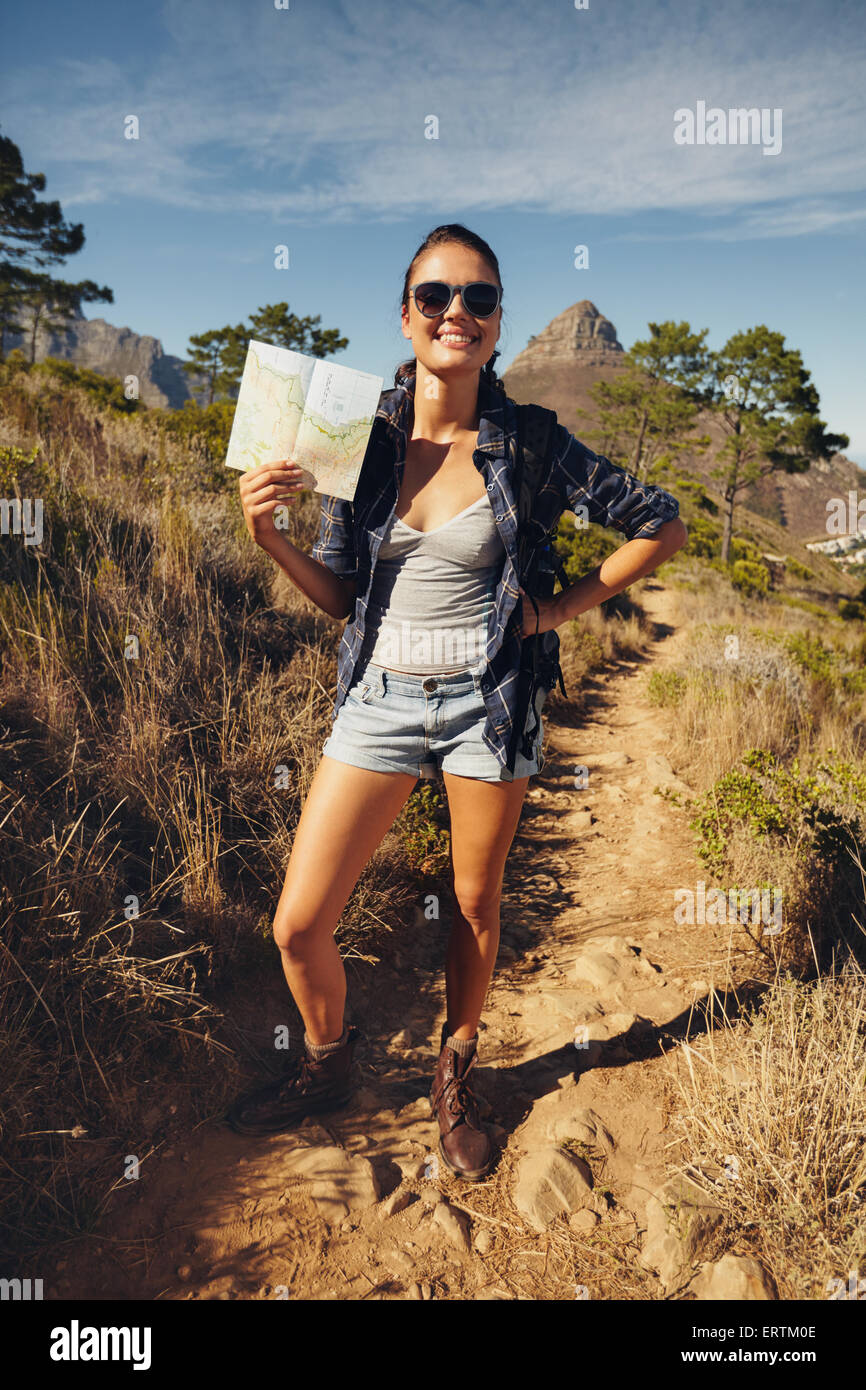 Portrait de la belle jeune femme posant à l'extérieur pour l'appareil photo montrant une carte. Caucasian female hiker sur le sentier chemin. Bonjour Banque D'Images