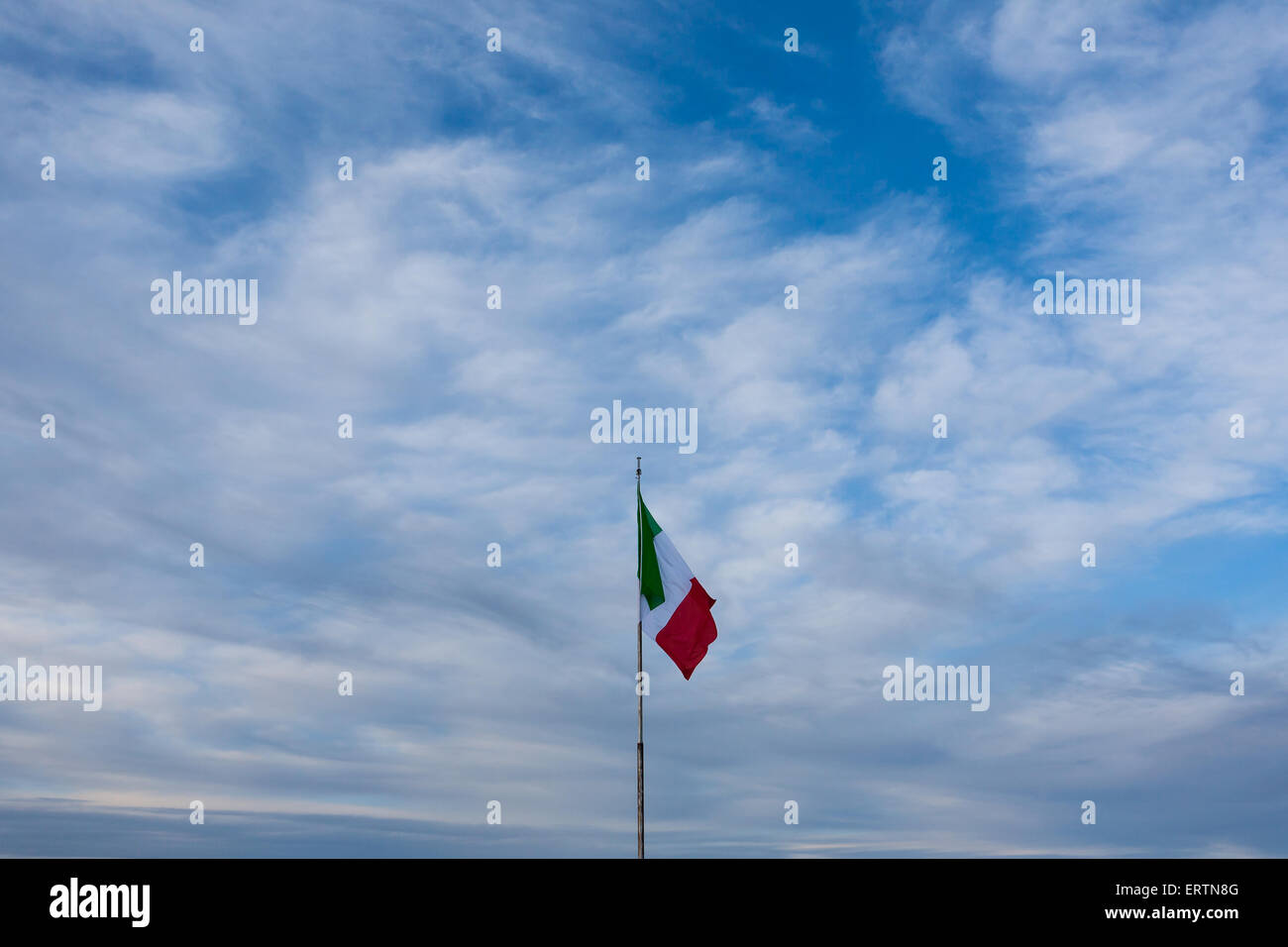 Un drapeau italien sur une blue cloudy sky Banque D'Images