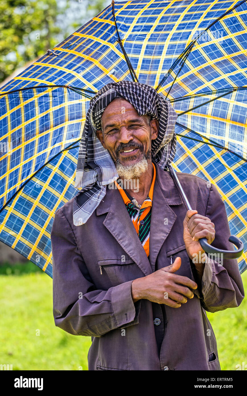Vieux homme éthiopien avec un parapluie sur une journée chaude. Banque D'Images
