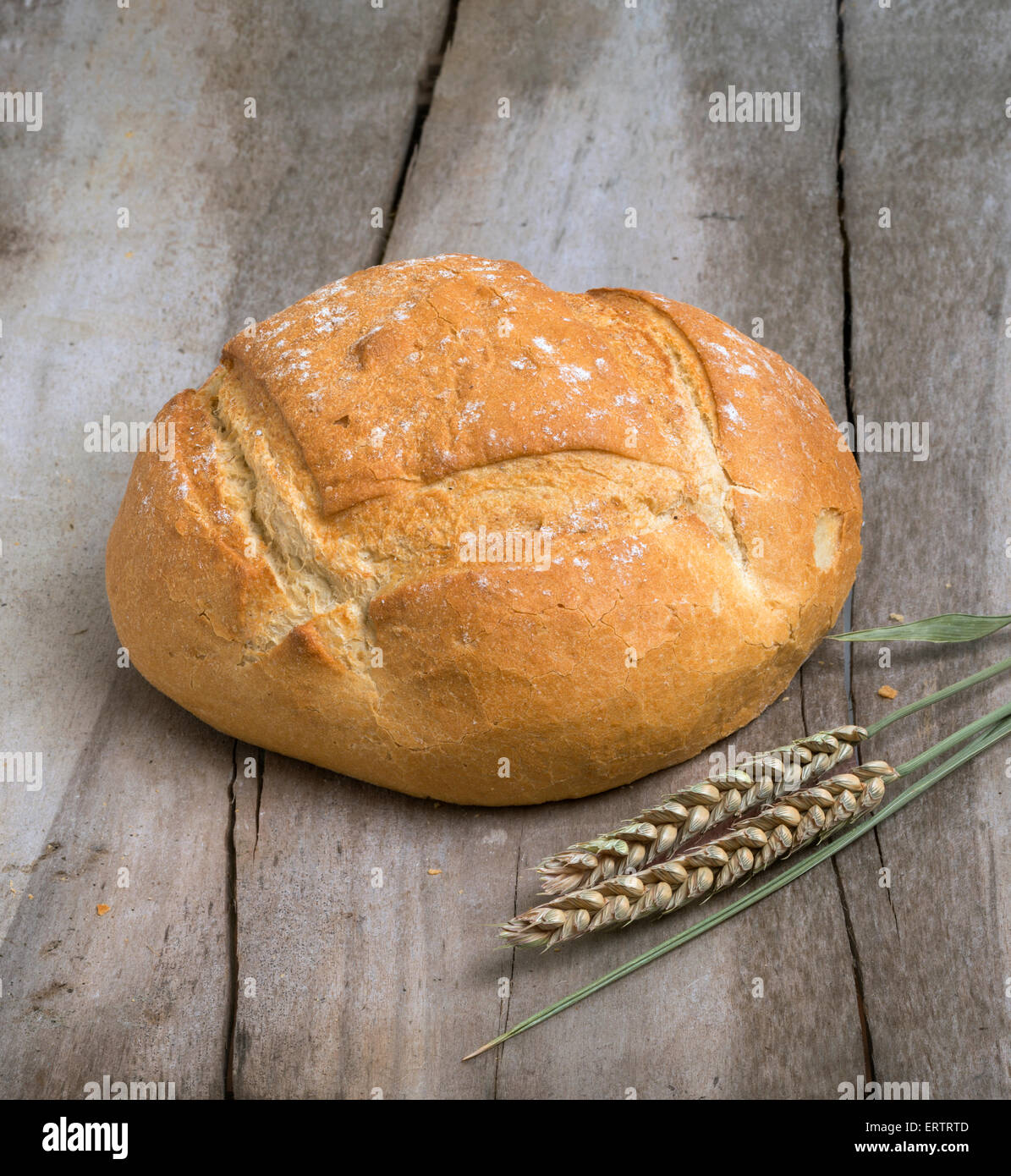 Miche de pain blanc sur une vieille table avec épi de blé Banque D'Images