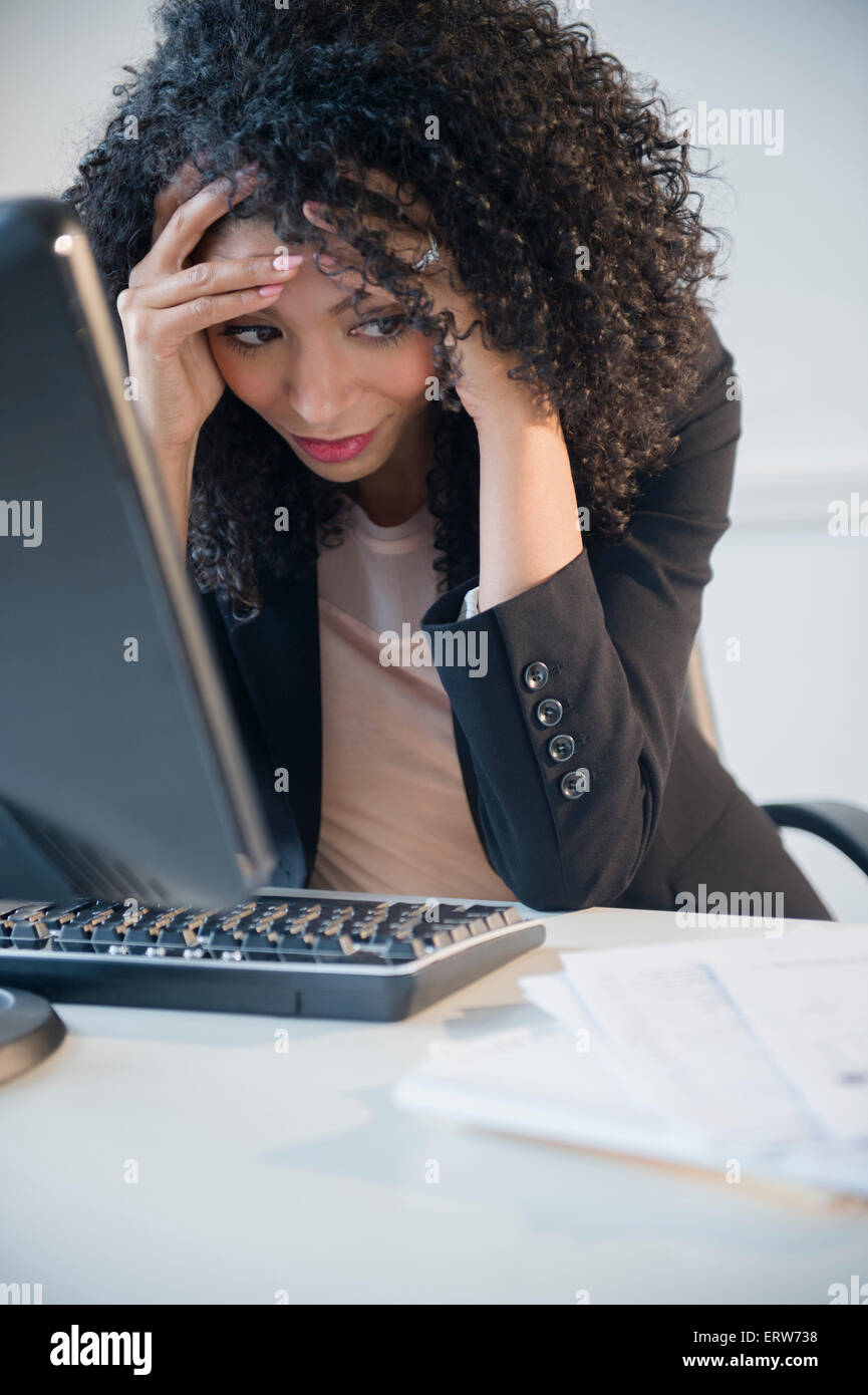 Frustrés mixed race businesswoman working at computer in office Banque D'Images