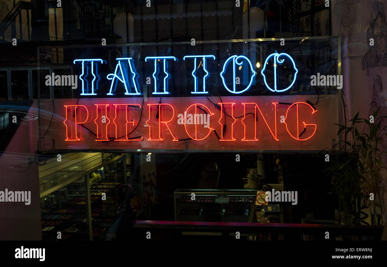 Une enseigne au néon dans la fenêtre d'une boutique de tatouage et piercing à New York City Banque D'Images