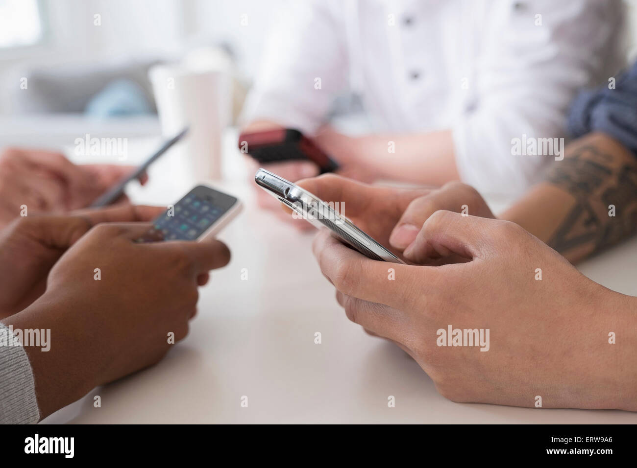 Close up d'amis des sms avec un téléphone cellulaire à table Banque D'Images