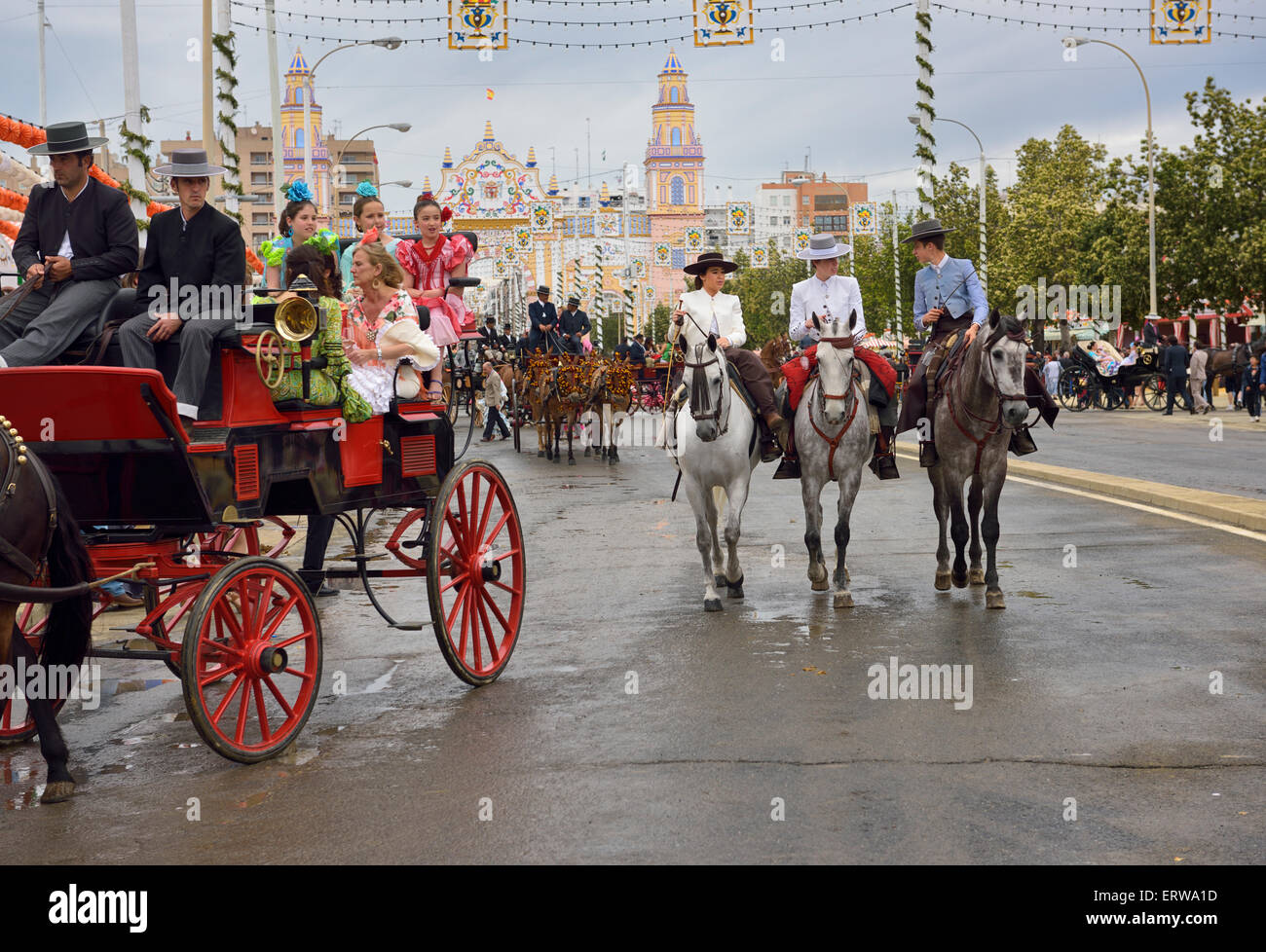 Mule calèches et cavaliers sur antonio bienvenida rue avec entrée principale 2015 foire d'Avril de Séville Espagne Banque D'Images