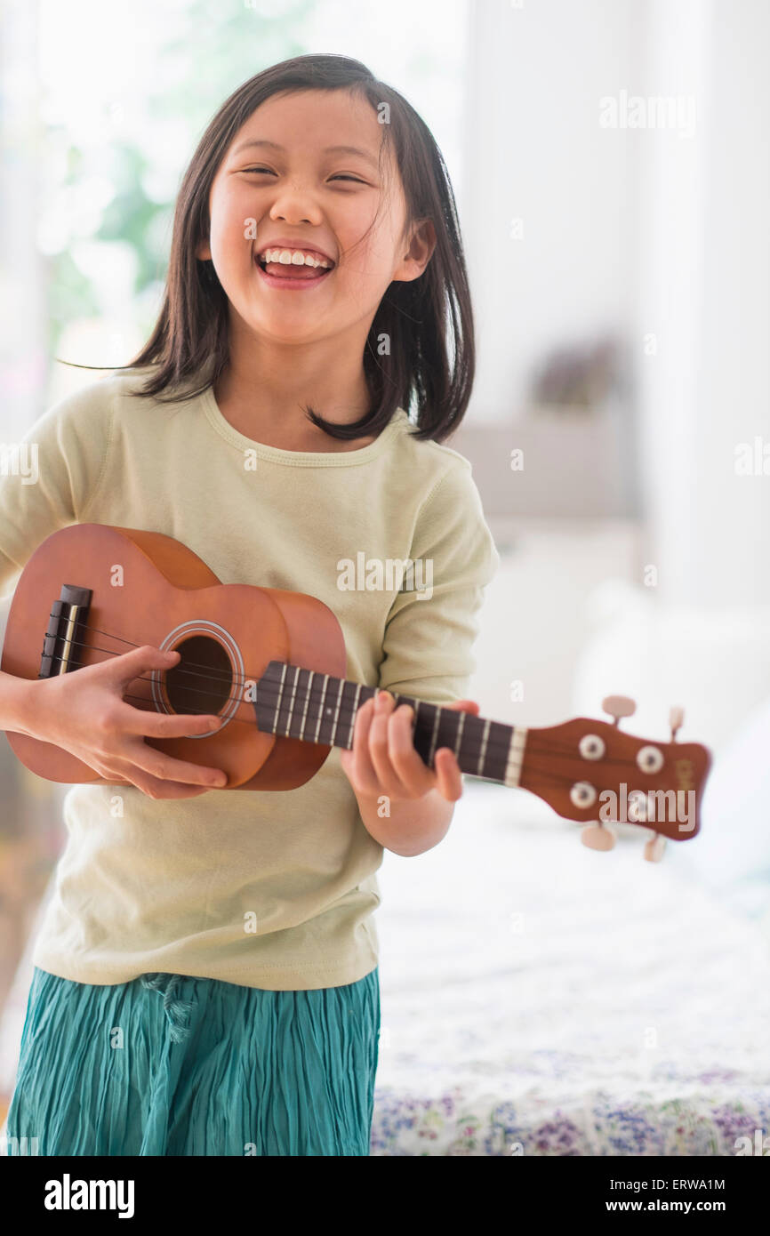 Jeune chinoise pratiquant ukulele dans la chambre Banque D'Images