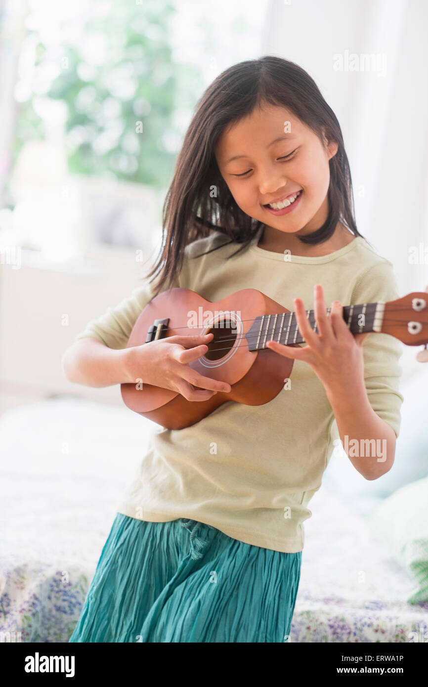 Jeune chinoise pratiquant ukulele dans la chambre Banque D'Images