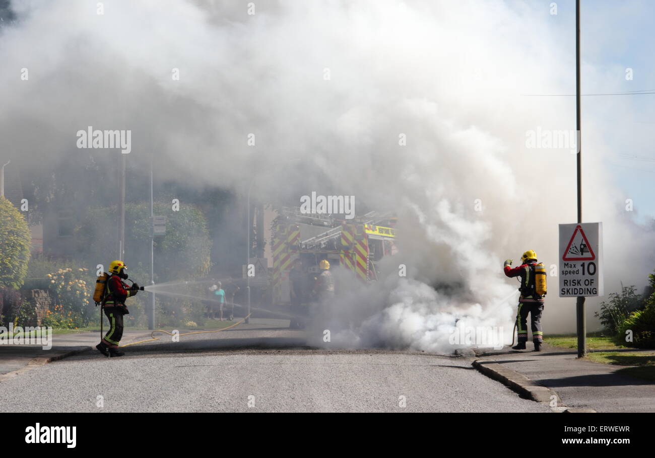 Les pompiers s'attaquer à un véhicule incendie sur une rue résidentielle dans le Derbyshire, Angleterre, RU Banque D'Images