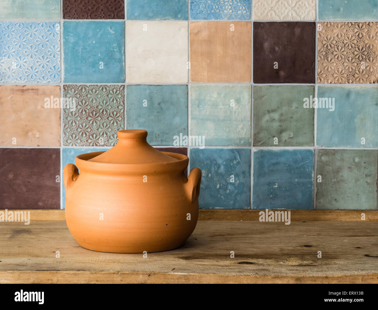 Pot en céramique fait main en face d'un mur carrelé de couleur dans une cuisine de campagne Banque D'Images