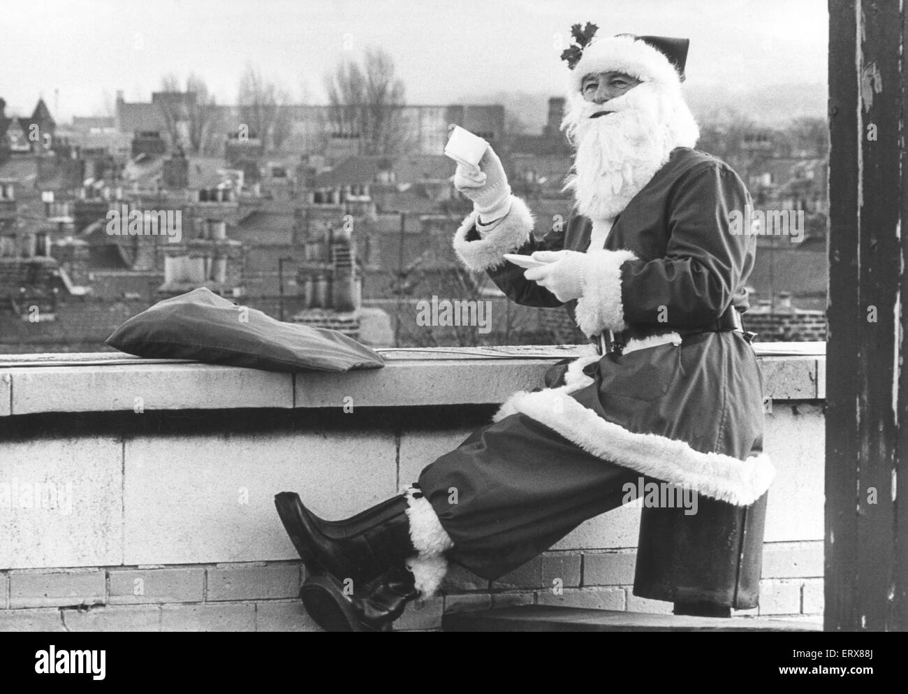 Le Père Noël ayant une tasse de thé bien méritée sur un toit, Teesside, 22 Décembre 1987 Banque D'Images