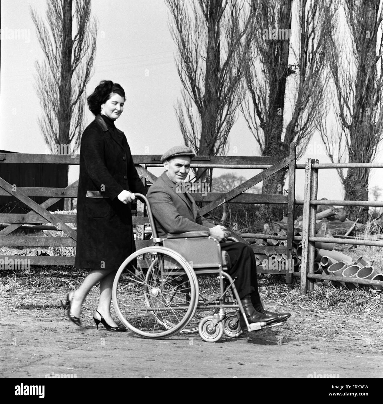 Jockey Champion Tim Brookshaw ne le matin en direction de sa colline de sternes, Shropshire, ferme dans son fauteuil roulant avec son épouse Joan. 19 mars 1964. Banque D'Images