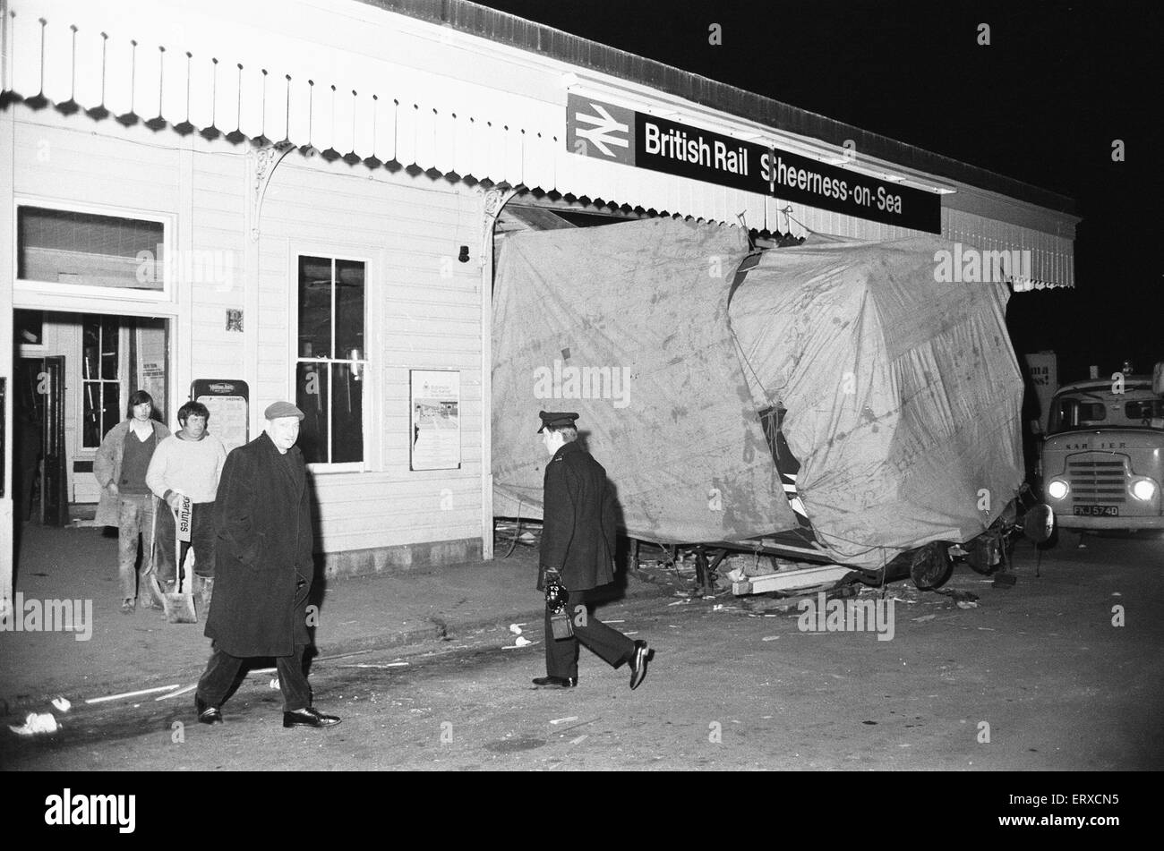 Accident ferroviaire à Sheerness-sur-Mer station : à 18:57 le vendredi 26 février 1971, 17:16 le service à partir de Victoria n'a pas réussi à arrêter. Par conséquent, les dix-transport train, démoli le tampon s'arrête, qui a envoyé le premier bogie avant l'entraîneur sans se briser sur le grand hall. Le coach a procédé à la démolition de l'hôtel de réservation de la moitié du bâtiment de la gare de bois, qui jusqu'à présent est demeurée pratiquement inchangée depuis son apparition en 1883. L'accident a entraîné un décès et 13. . L'image montre des ouvriers quittant la gare comme la cabine du train est couvert. Banque D'Images