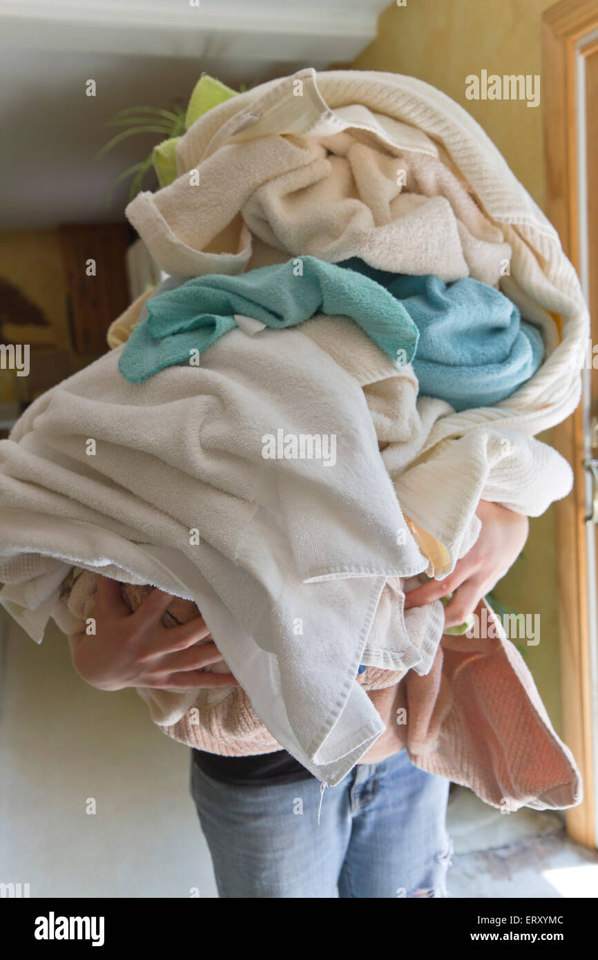Une femme portant une énorme charge de serviettes sales sur jour de lessive Banque D'Images