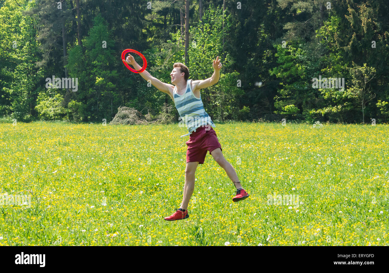 Jeune homme attraper frisbee in meadow, Perlacher Forst, Munich, Bavière, Allemagne Banque D'Images