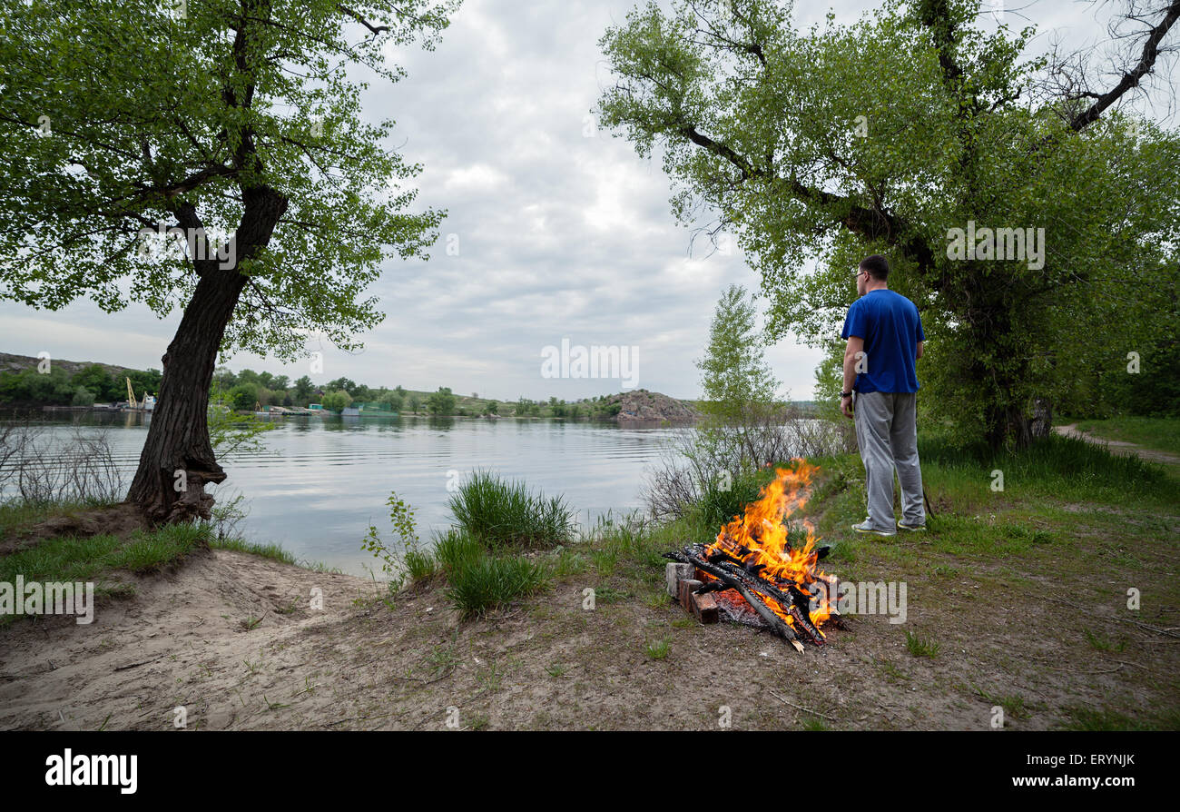 L'homme et de feu de forêt au printemps. Les charbons de feu. Crépuscule en Ukraine Banque D'Images