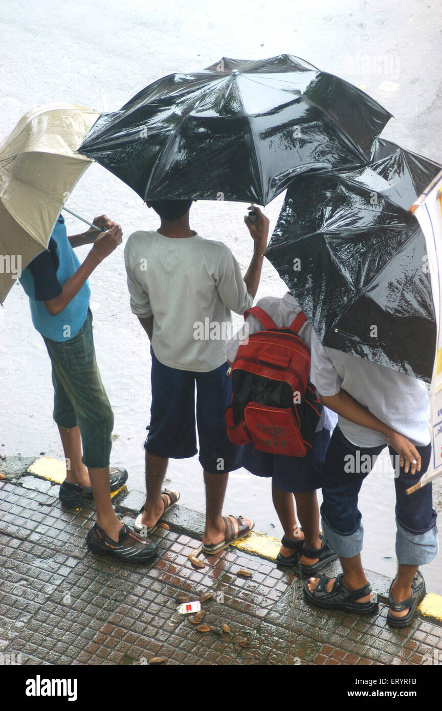 Enfants debout avec des parasols sous la pluie , Bombay , Mumbai , Maharashtra , Inde , mousson indienne , Asie Banque D'Images