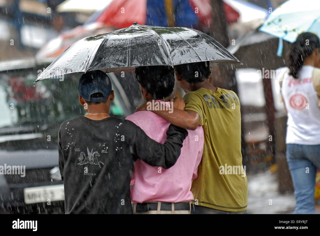 Trois amis sous un parapluie sous la pluie ; Bombay , Mumbai ; Maharashtra ; Inde , asie Banque D'Images