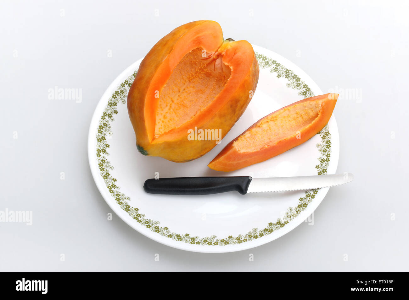 Fruits de papaye Carica papaya latine ; slice et couteau sur une plaque blanche Banque D'Images