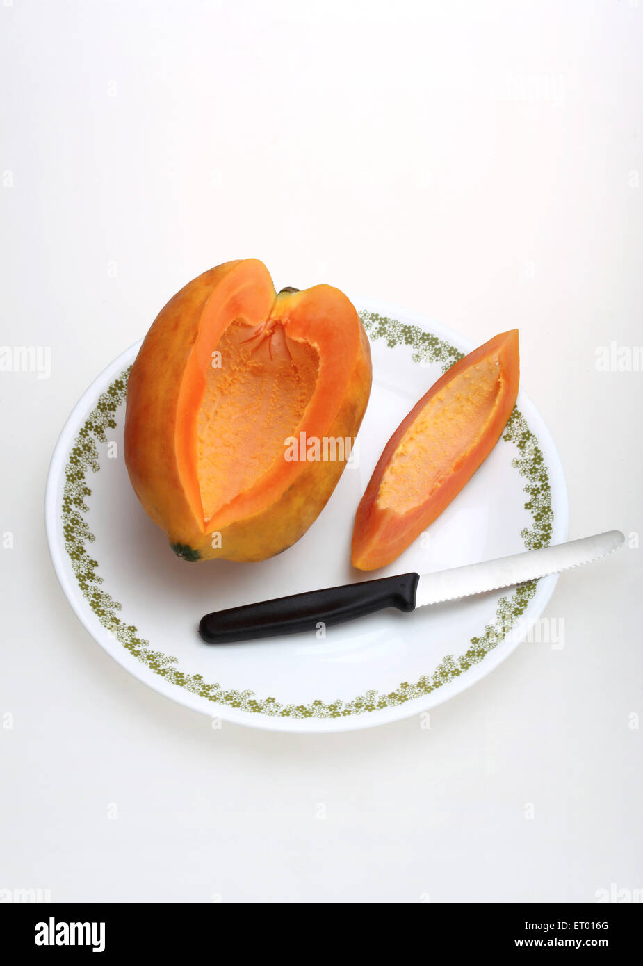 Fruits de papaye Carica papaya latine ; slice et couteau sur une plaque blanche Banque D'Images
