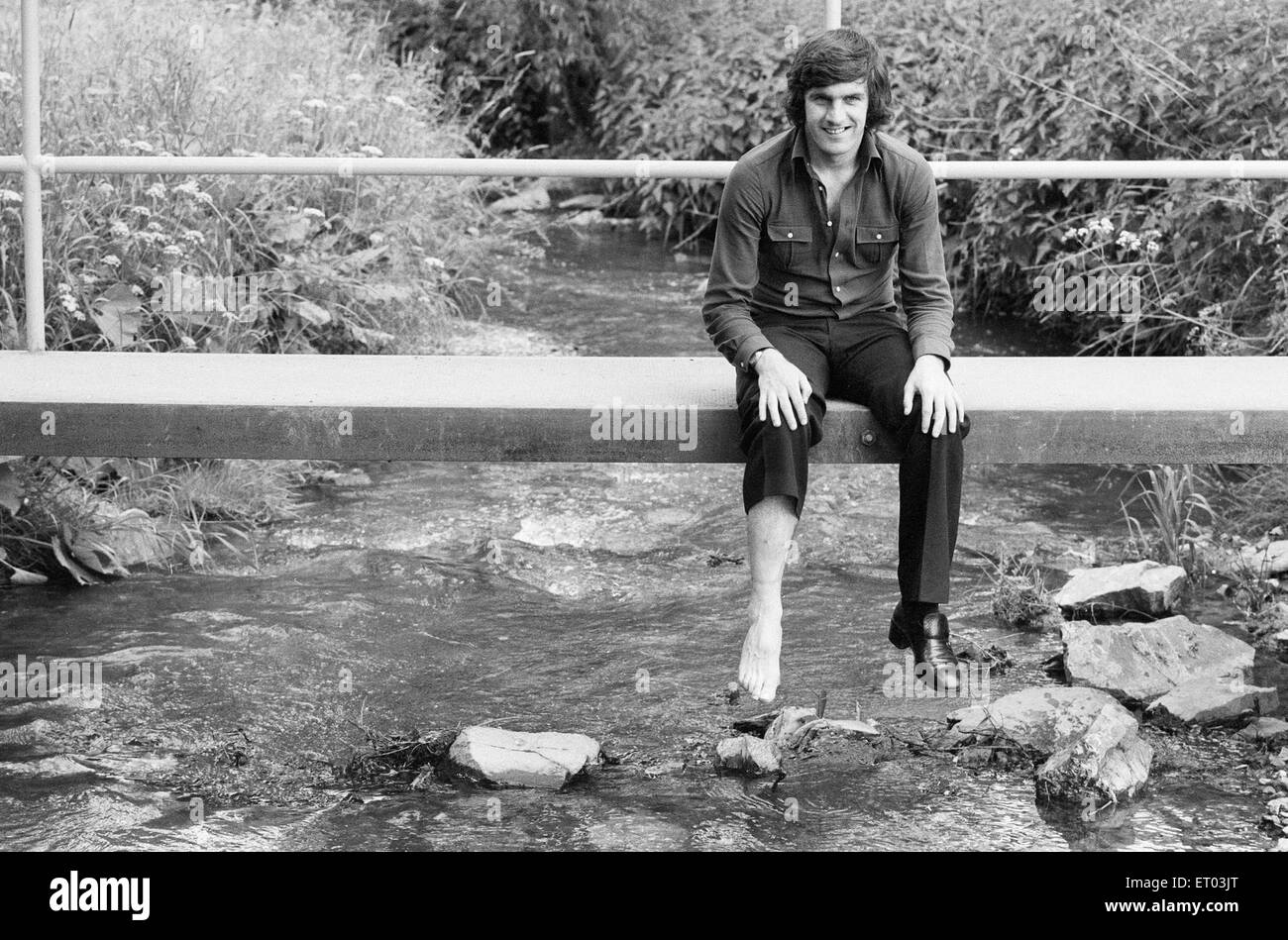 1974 Tournoi de Coupe du Monde en Allemagne de l'Ouest. L'équipe de football de l'Ecosse de détente à leur hôtel Weilnau à Francfort. Peter Lorimer assis sur un petit pont sur un ruisseau. 17 juin 1974. Banque D'Images