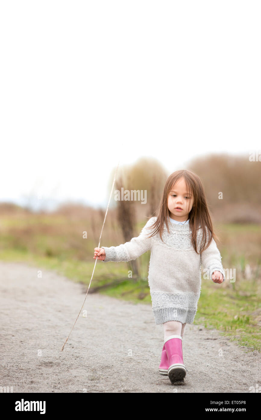 Girl in pink bottes marcher avec stick Banque D'Images