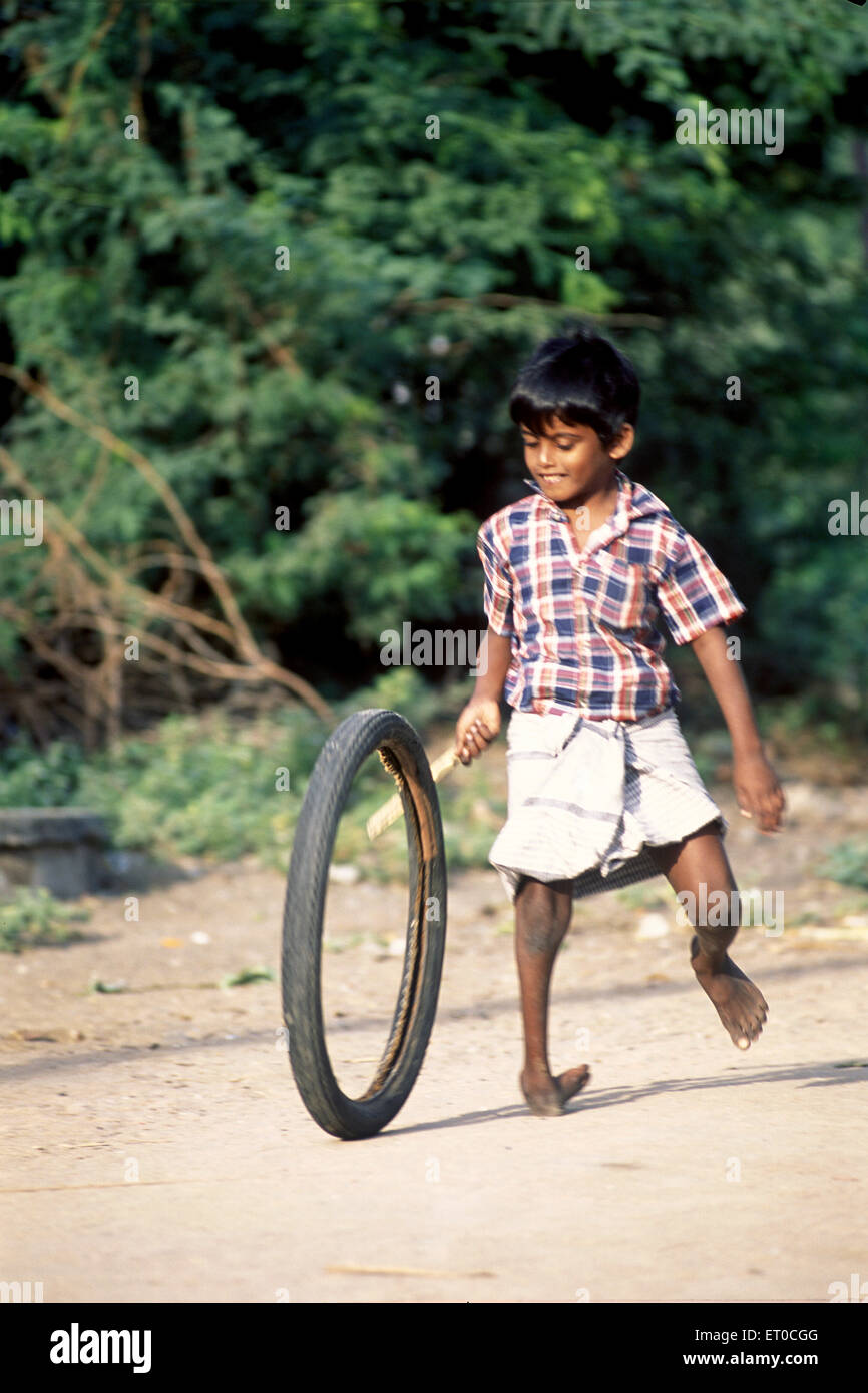 Polio, poliomyélite, poliovirus, garçon handicapé jouant avec un pneu en caoutchouc ; Tamil Nadu ; Inde , asie Banque D'Images