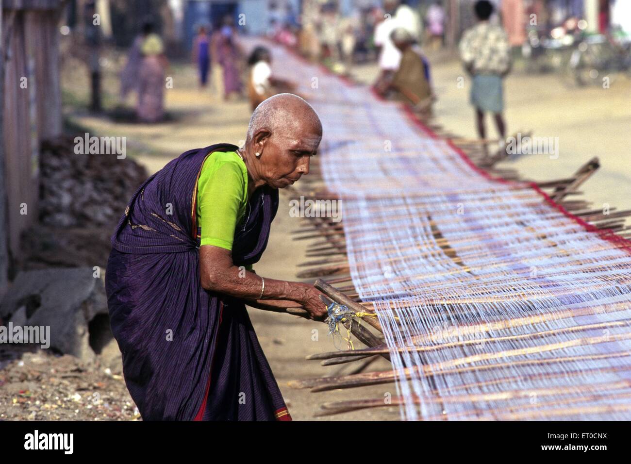 Vieille Femme dépose de noeuds et de séchage serviette de coton à fil ; Kanchipuram Tamil Nadu Inde ; PAS DE MR Banque D'Images