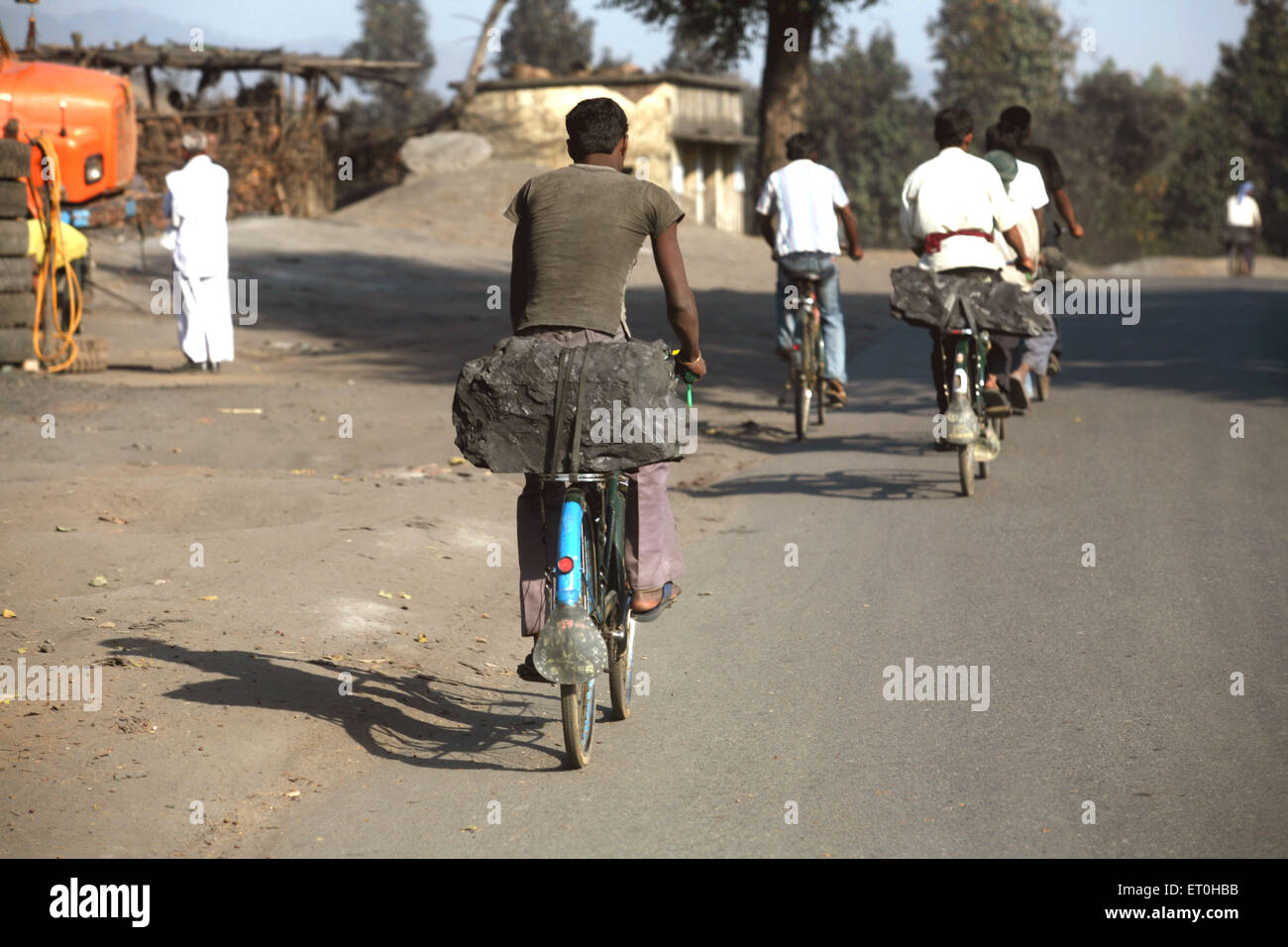 Les travailleurs de mine de charbon transportant bloc de charbon chargés siège arrière de bicyclettes au Jharkhand en Inde ; Banque D'Images