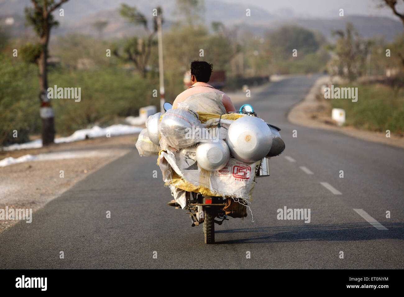 Laitier équitation sur deux roues transportant des bidons de lait ; Inde Banque D'Images