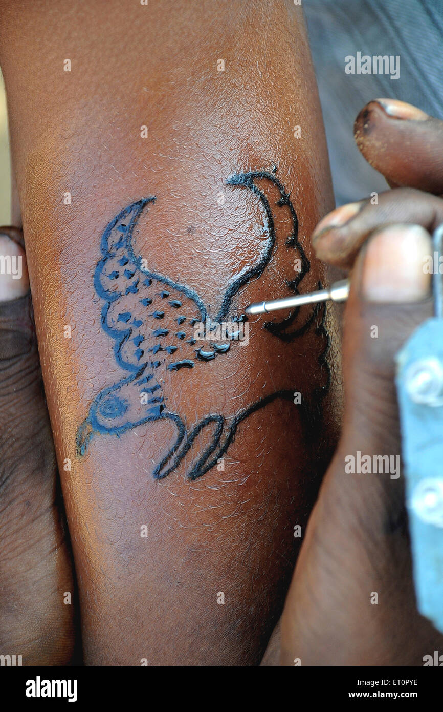 Homme faisant le tatouage d'aigle sur la main ; Foire de Pushkar ; Rajasthan ; Inde Banque D'Images