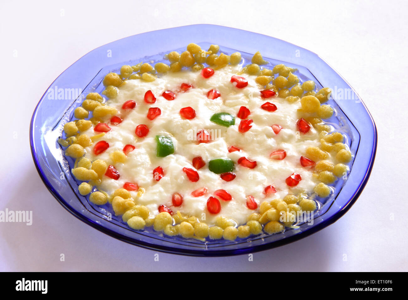 Salade de fruits et légumes ; grenade anar boondi raita dans un bol en verre rond bleu sur fond blanc Banque D'Images