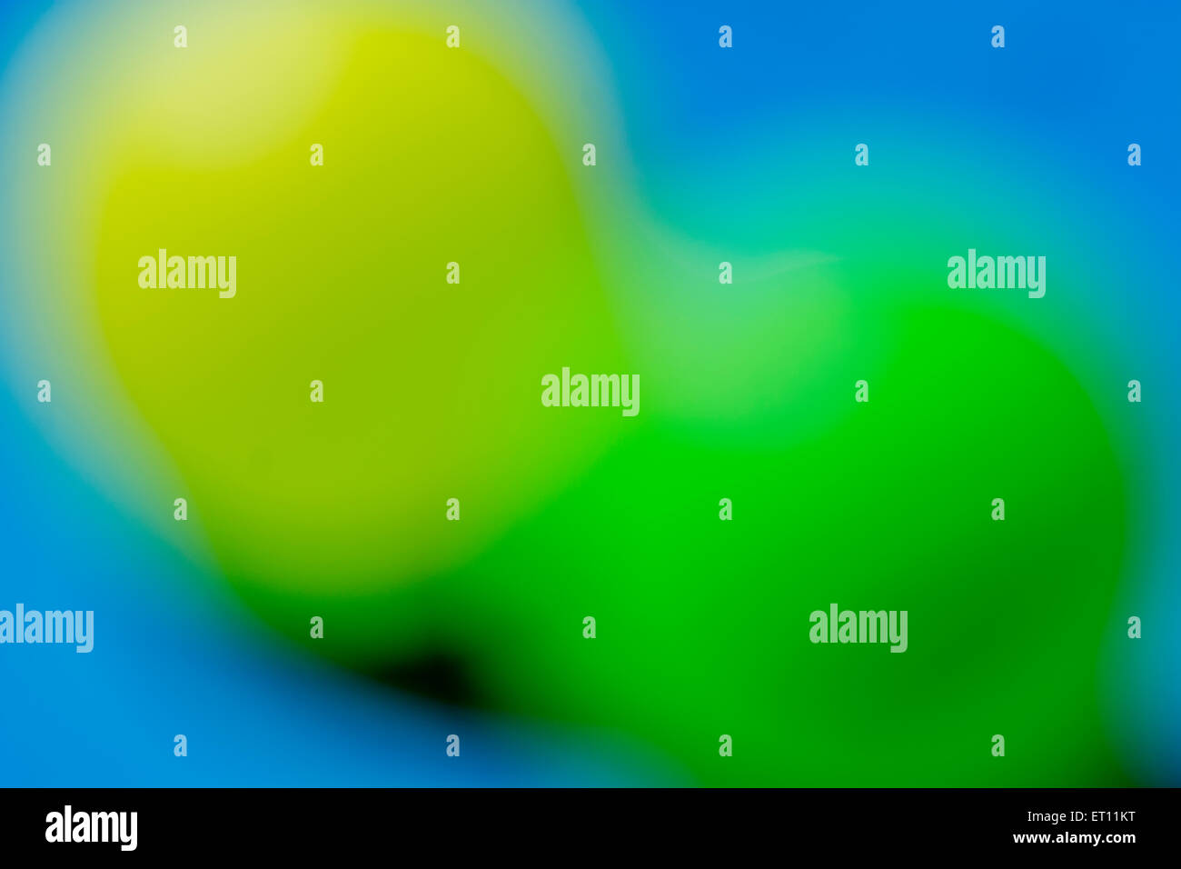 Abstrait, hors focale, sphères jaunes et verts contre fond bleu ciel. Banque D'Images