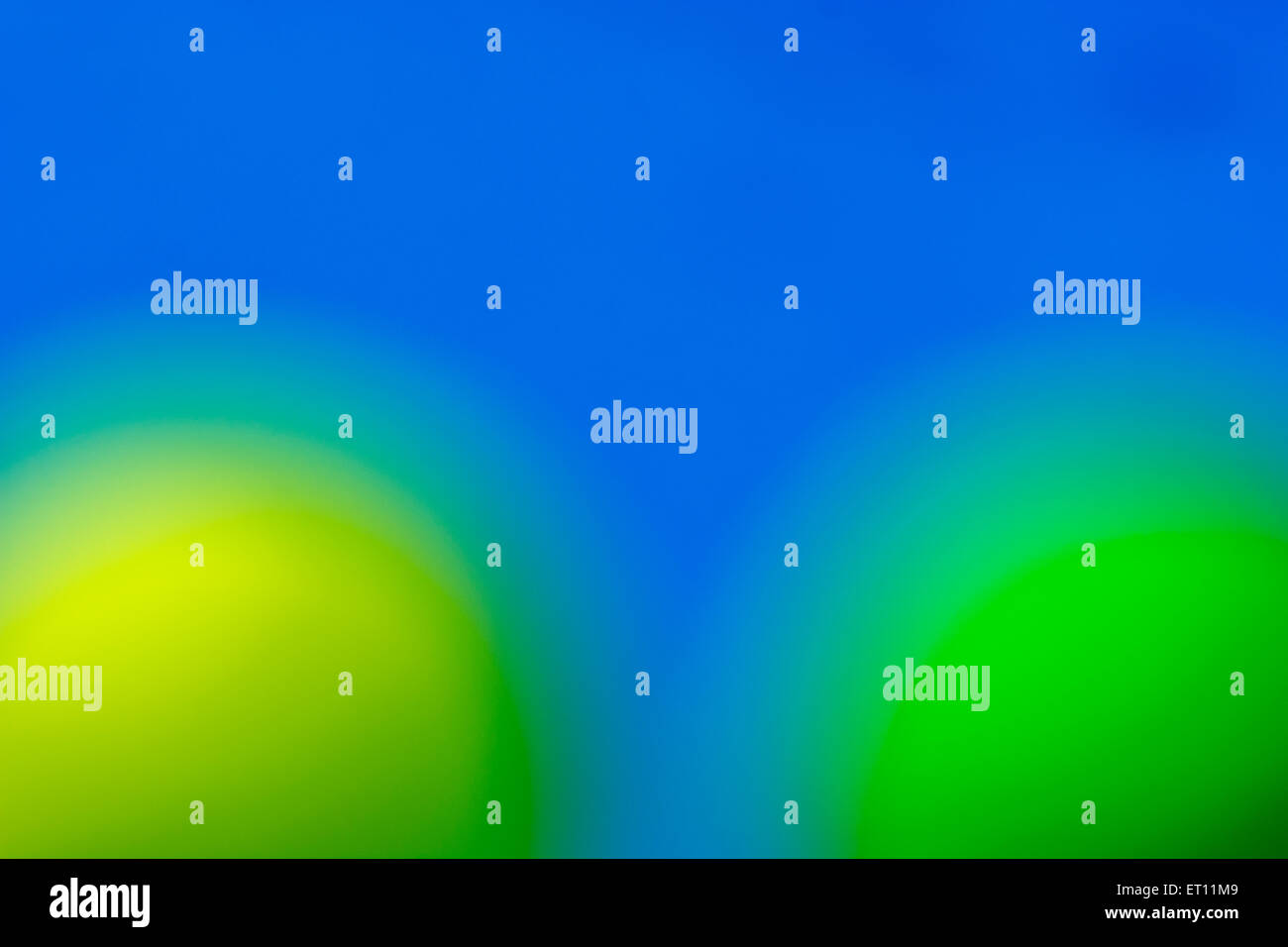 Abstrait, hors focale, sphères jaunes et verts contre fond bleu ciel. Banque D'Images