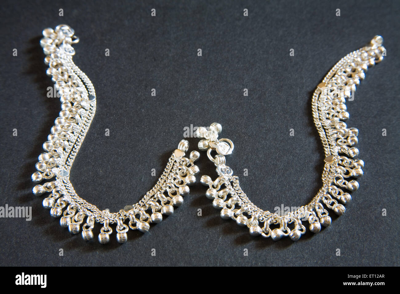 Chaînettes cheville argent paire sur fond noir Banque D'Images