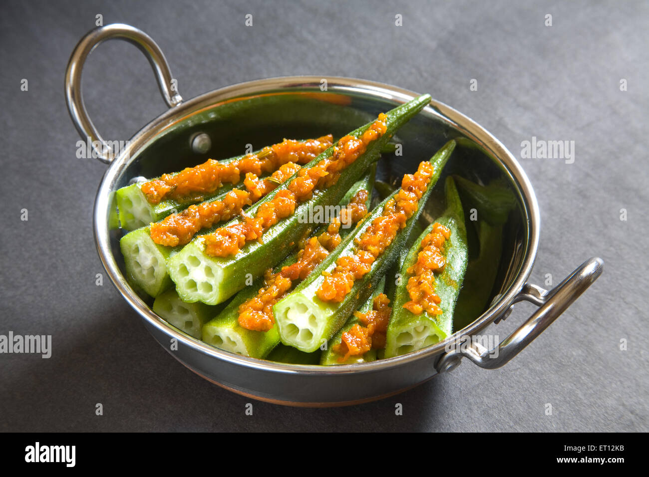 La cuisine indienne de trucs chers Hibiscus esculentus gombo de doigt en acier kadahi sur fond noir 17 Mai 2010 Banque D'Images