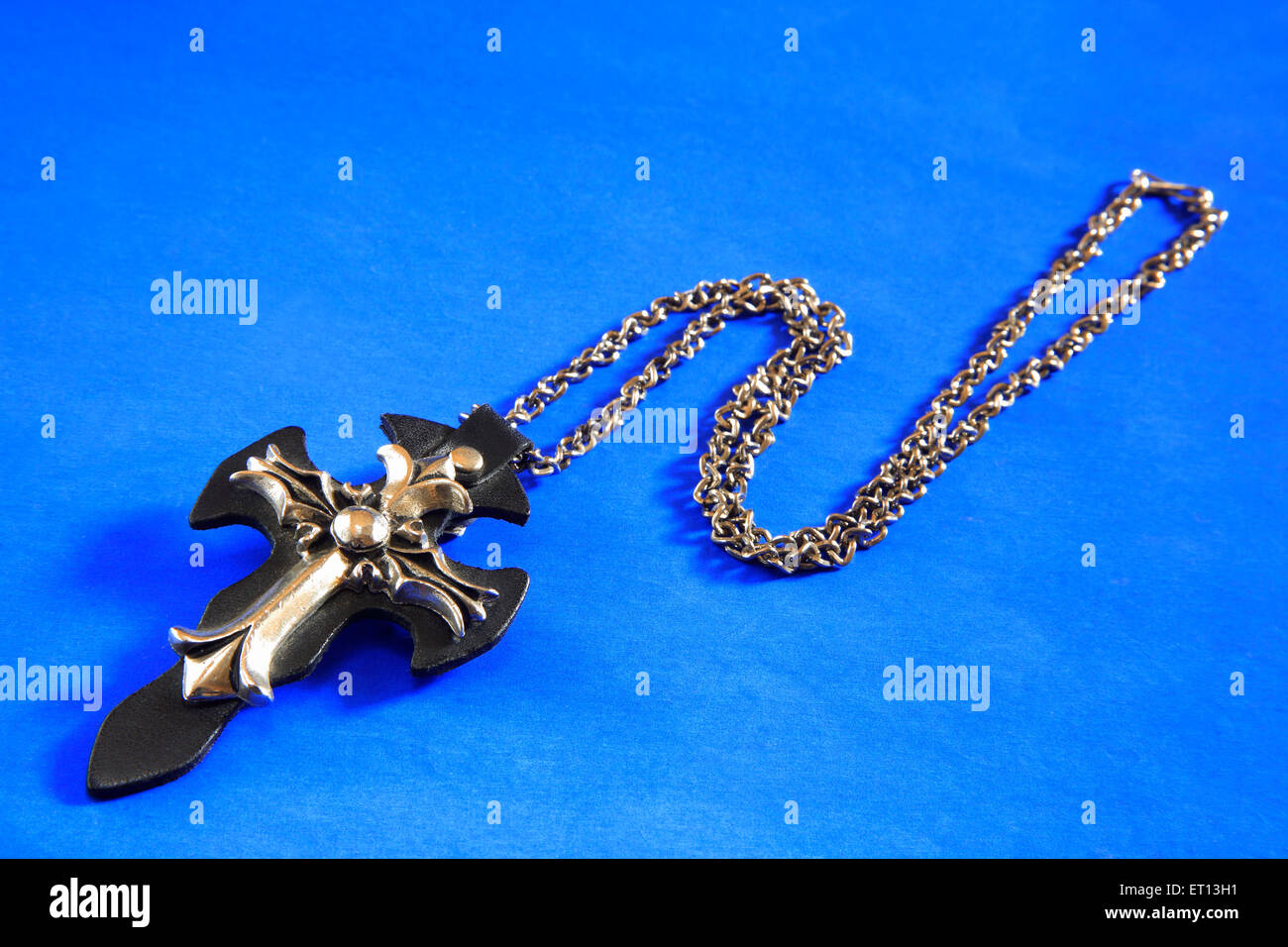 Collier avec pendentif en croix amulette sur fond bleu Banque D'Images