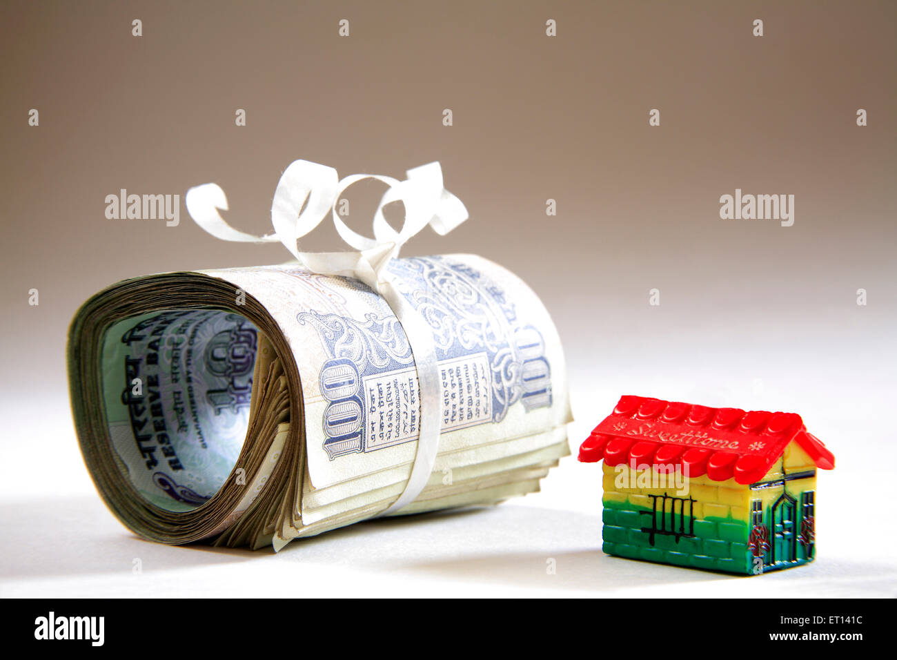 Modèle en plastique accueil et paquet de cent roupies notes sur fond blanc Banque D'Images