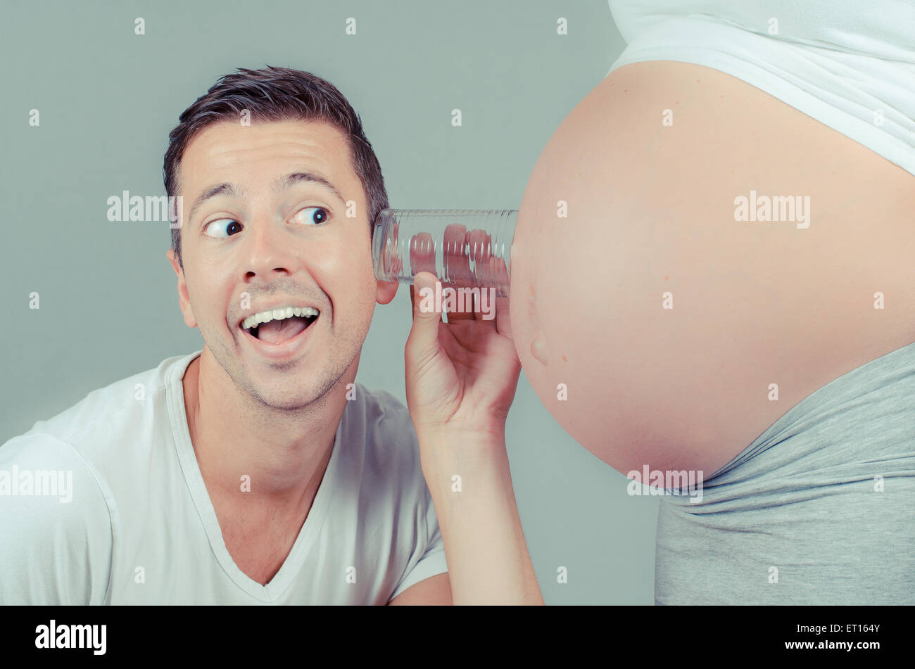 Drole De Pere A L Ecoute Avec Un Verre Sur Le Ventre De Sa Femme Enceinte Photo Stock Alamy