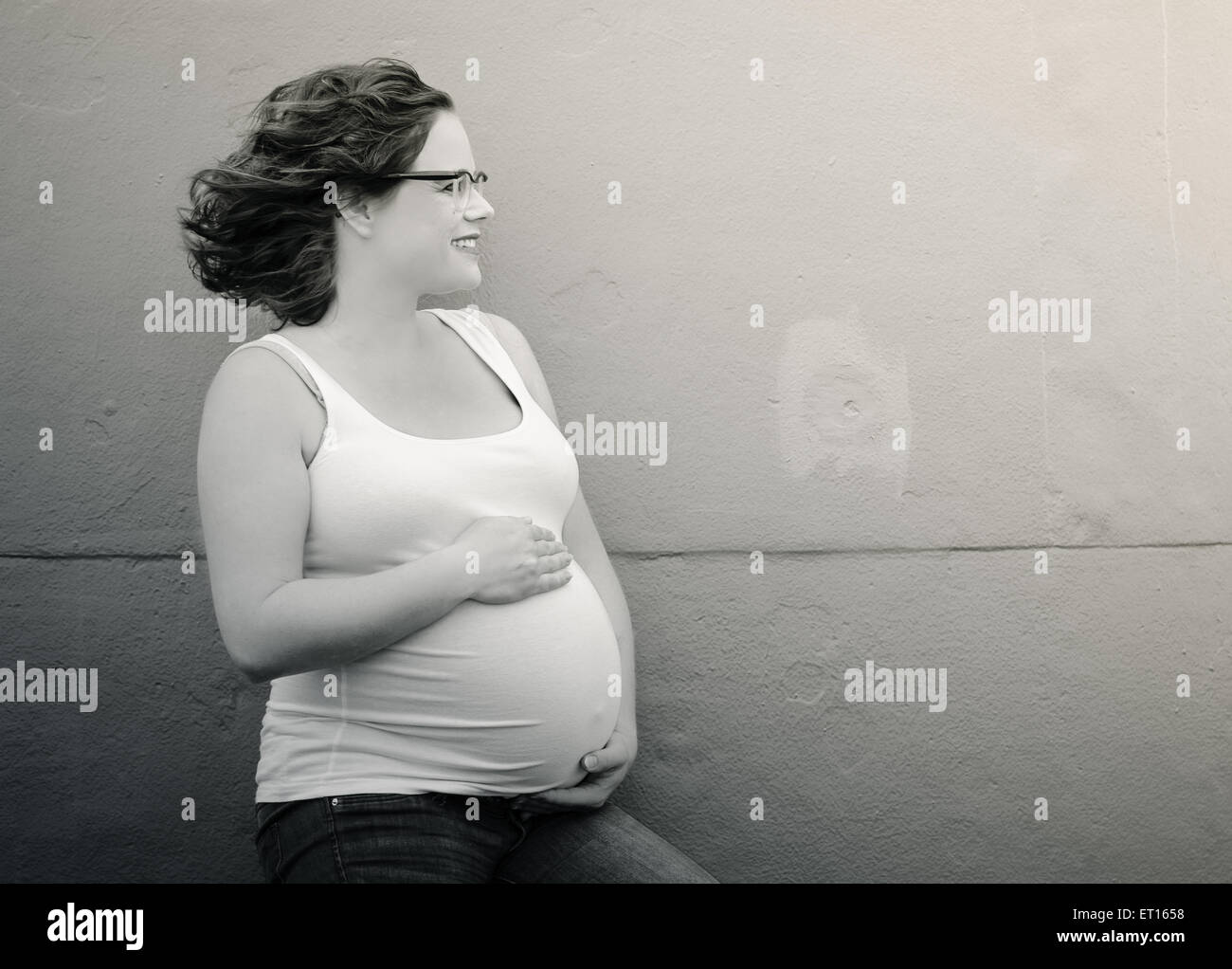 Femme enceinte devant un mur en situation urbex Banque D'Images